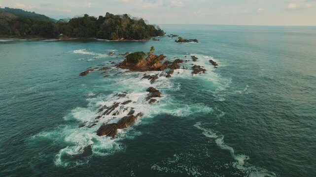 Small rocky island and nearby coastline at sunset over Dominicalito beach Costa Rica