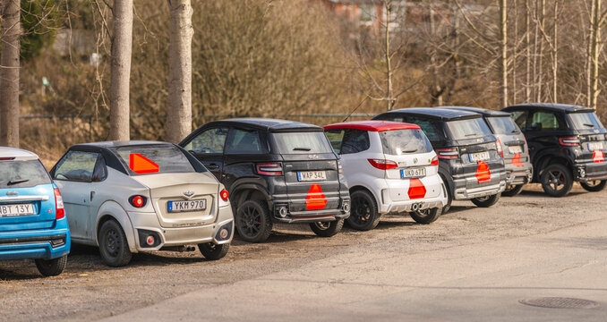 Kungsbacka, Sweden - March 20 2026: Row of compact microcars parked on gravel roadside in daylight.