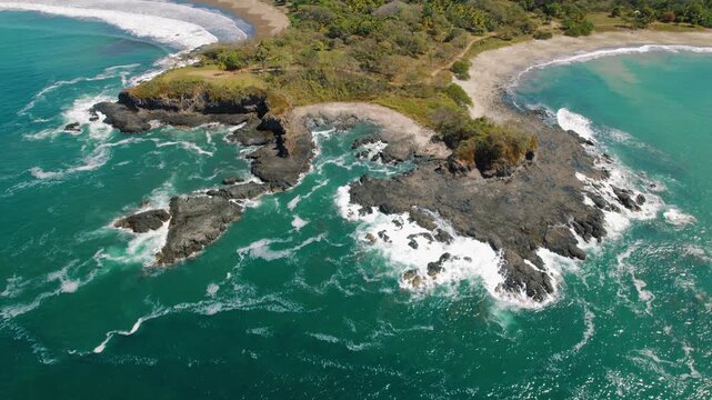 Waves crashing around rugged coastal cliffs in a remote tropical Pitahaya beach