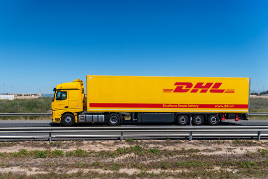 Tarragona,Spain, 4/15/2026; Truck with DHL branding, multinational parcel and groupage company, driving on a highway.