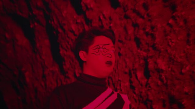 Man with Spider Makeup in a Hellish Red-Lit Cave