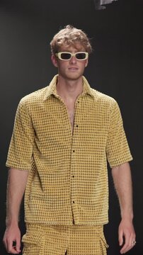 Fashion week, man and walk with sunglasses on runway for clothes showcase, couture or designer brand. Catwalk show, model and trendy wardrobe on stage for summer collection, menswear and confidence