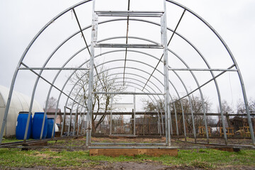 Naklejka premium Metal frame of a greenhouse in a private garden, land plot in spring