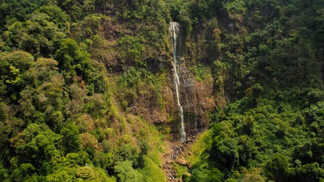 Tall waterfall Catarata Diamante cascading down a lush green cliff in Costa Rica
