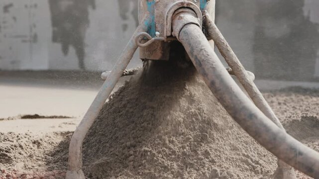 Pouring semi dry floor screed mix from machine onto surface close up