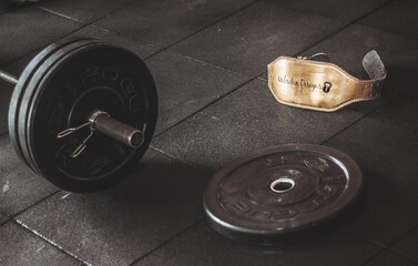 Obraz premium Professional heavy iron dumbbells and kettlebells on a rack in a dark moody industrial gym, close up of strength training equipment for bodybuilding and fitness workout with dramatic lighting.