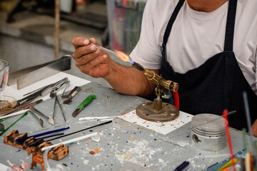 Fototapeta premium Glass blower artist working with a gas torch in workshop, Handmade glass art craft process, Master craftsman shaping molten glass with fire, Small business and traditional creative hobby concept