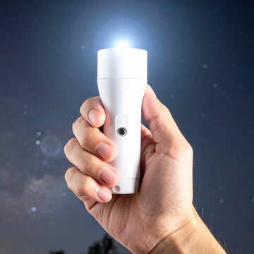 Hand holding glowing white flashlight in dark night sky, exploring discovery, illumination, searching guidance, travel survival, safety equipment