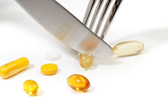 Eat pills with fork and knife on a white background