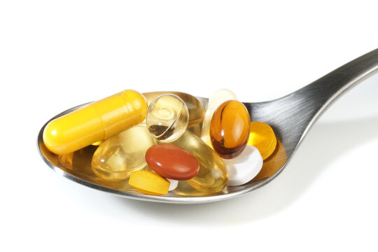 Pills on a spoon on white background