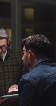 Back, tablet and men in meeting, conversation and planning for schedule, research and web designer. Business people, night or employees in office, teamwork or tech for online reading or company app