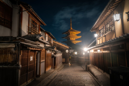 View of Yasaka Pagoda at night with traditional wooden houses and glowing lanterns along a stone-paved street Kyoto, Kyoto, Japan.