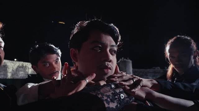 A close-up of a young man's face as he is held and surrounded by the hands of his followers or cult members. An intense, dramatic, and mysterious scene of adoration or control at night.