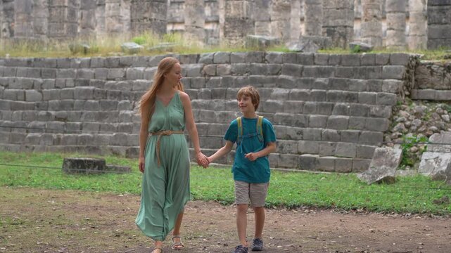 Woman and her 10 year old son walking along the colonnade of the Temple of the Thousand Columns in Chichen Itza, Mexico. Slowmotion video.