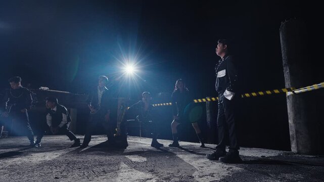 A stylish man walks through his crew, who are posing in a derelict building. The low-angle tracking shot and dramatic backlight create a powerful and cinematic music video aesthetic.