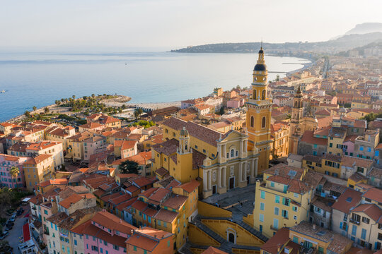 Aerial view of Menton, France, old town and Basilica of Saint Michel by the Baie de Garavan, marina left, terracotta roofs, late afternoon light, Mediterranean Sea.