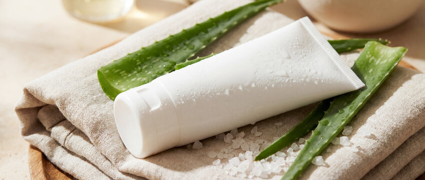 summer luxury skincare sunscreen aloe spa towel wellness closeup natural body care with white bottle and fresh green leaves suggesting beach protection hydration clean beauty and resort self care