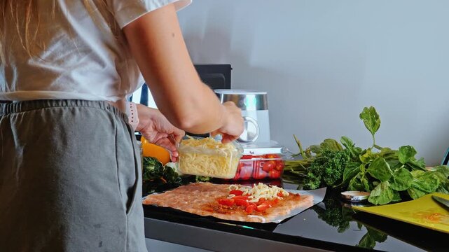 Woman putting grated cheese on raw minced chicken meat, kitchen environment, preparing homemade meal, culinary process, healthy food preparation.