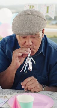 Happy, grandfather and blower with child at birthday party for celebration, gathering and bonding. Smile, old man and blowing horn for outdoor fun, grandchild laughing and support at special occasion
