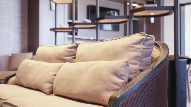 Close-up technical shot of high-quality fabric weave and dark wood framing on furniture, pulling back to a shallow depth-of-field lounge background.