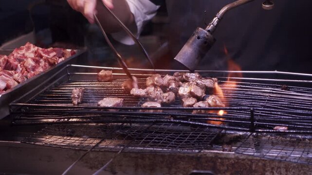 Close up of a the hands of a man cooking chopped beef with a blow torch to sell as street food at a night market in Kaohsiung, Taiwan.