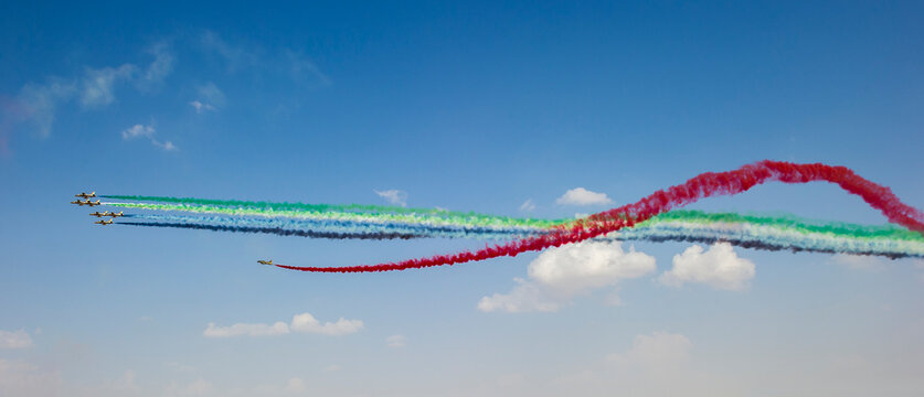 The UAE Air Force aerobatic team, Al Fursan, painting the sky with colorful smoke trails in the national flag colors.