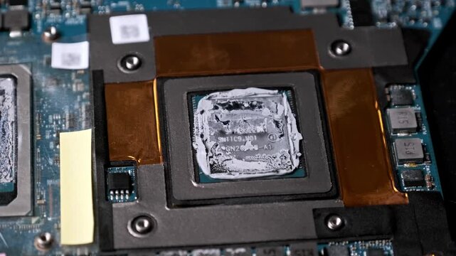 An extreme close-up zooms into a laptop CPU die covered with thermal compound. The intricate details of the silicon chip and motherboard components highlight precision engineering.
