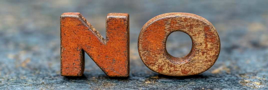 Close-up macro photograph of weathered, rustic wooden letters spelling out 'NO' against textured, out-of-focus background, symbolizing rejection and refusal.