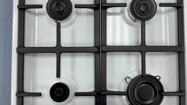 White gas stove closeup with grates, clean enamel surface, cast iron burners and glossy finish installer inspection and showroom
