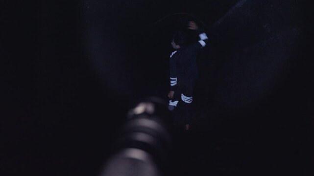 A classic horror movie "jump scare" scene. From a first-person POV, a flashlight finds a man in a dark cave who performs a scary dance before suddenly lunging directly at the camera.
