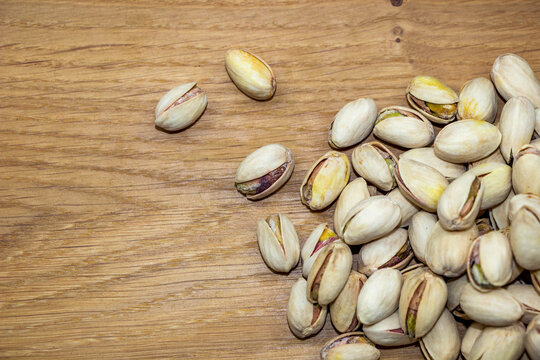 salted pistachios piled in  hill on a wooden board, light brown, texture, nutritious, close-up, healthy nuts