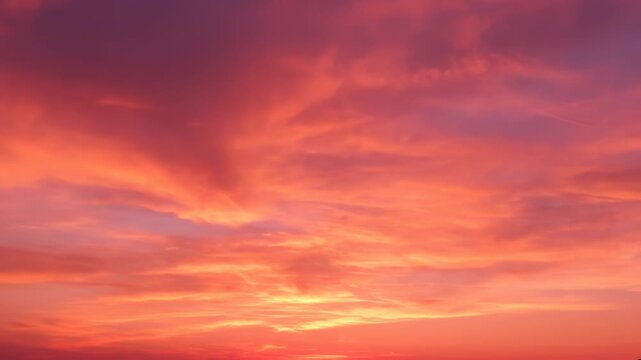 A vibrant sunset sky, featuring a gradient of reds and oranges through wispy, dynamic clouds