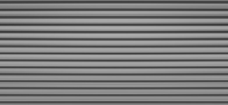 building is lined with square panels. metal sheet wall cladding with scalloped design. corrugated sheet, dark gray, riveted. horizontal stripes, shadows, corner, fence, aluminium, sheet