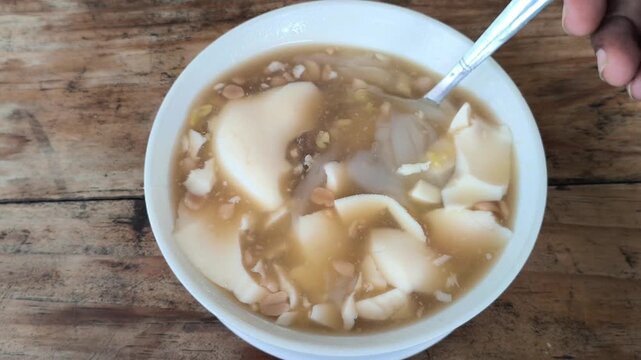 Enjoying a warm bowl of tahuwa, a soft tofu dessert with a silky texture, offering comforting taste and health benefits, rich in protein and perfect for a soothing treat.