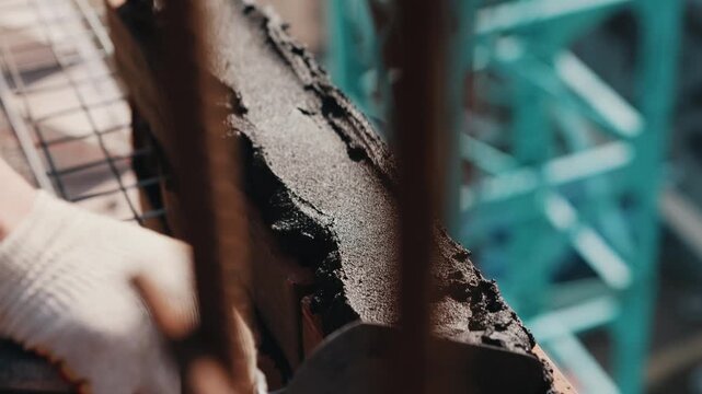 Applying mortar along brick row with trowel during wall construction close up