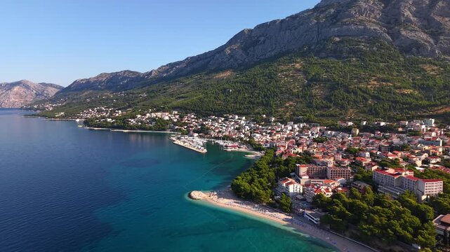 Aerial view of the coastal town of Baska Voda on the Makarska Riviera in Croatia, featuring the Adriatic Sea, pebble beaches, and the Biokovo mountain range