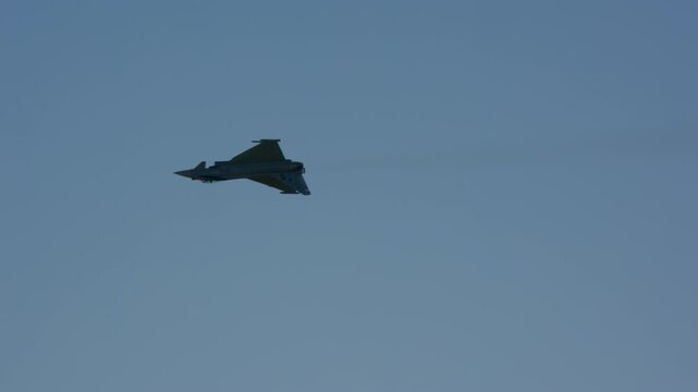 Military fighter jet seen from directly below in level flight, full underside detail with delta wing and canard visible, slow motion, pale sky