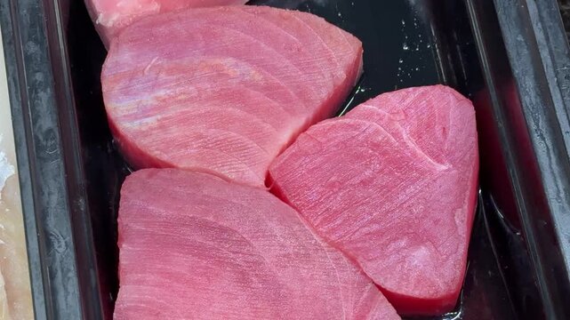 Small, young tunas, whole, with the head, chilled on shallow ice at the seafood market. An open shelf at the fish market. Close-up