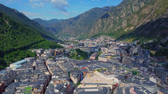 aerial perspective captures the vibrant cityscape of Andorra La Vella nestled within the majestic Pyrenees mountains. This footage showcases the unique blend of urban development and natural beauty, h