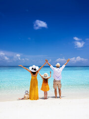A happy family stands on a tropical paradise beach with turqouoise sea and fine sand in the Maldives islands as a concept for travel and vacation © moofushi