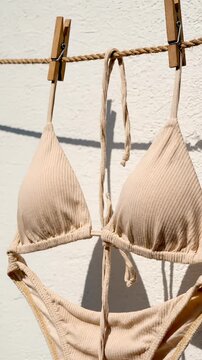 Stylish bikini hanging on clothesline. Sunlight illuminates fabric, showcasing texture and design. Vertical orientation enhances visual appeal. Perfect for summer fashion.