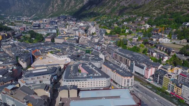 aerial drone shot showcasing the vibrant urban landscape of Andorra la Vella, the capital city of Andorra, nestled within the stunning Pyrenees mountains. This footage captures the unique blend of cit