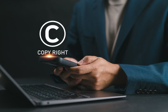 Businessman using smartphone with glowing copyright symbol, representing digital copyright protection, intellectual property rights, online content ownership, and digital rights management.