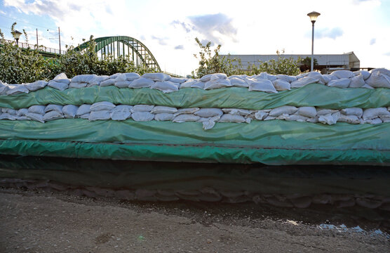 Wall of Sandbags and Tarp Plastic for Floods Protection Near River Arch Bridge