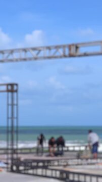 Workers dismantle stage structure after beach festival in Nha Trang. Event teardown concept in Vietnam seaside, crew removing metal truss, post concert cleanup. Blurry real time footage.