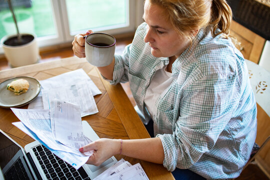 Woman managing household bills at home kitchen table