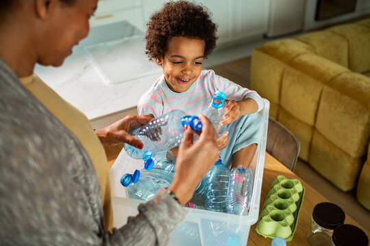Parent and child recycling plastic bottles in kitchen