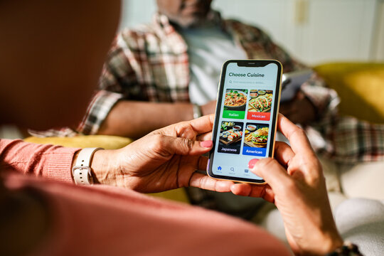 Woman choosing cuisine on food delivery app at home