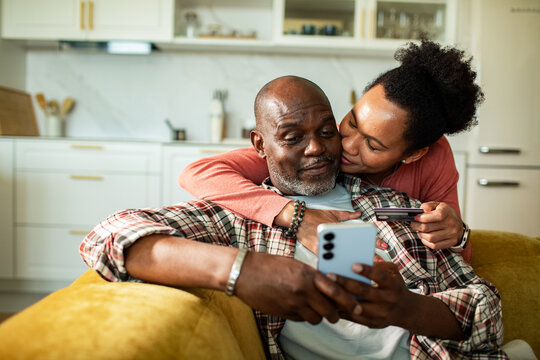 Affectionate couple shopping online with credit card on home couch