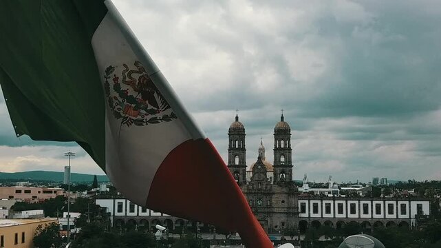 Mexican flag waving in front of the church in the city of Guadalajara, land of tequila 
